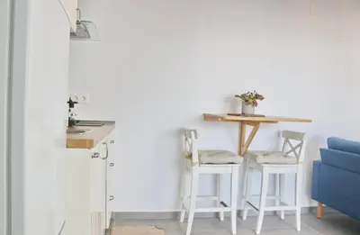 a kitchen with a table and two white stools at Villa Buganvilla in Conil de la Frontera