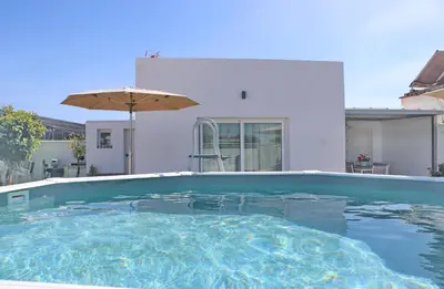 a swimming pool in front of a house with an umbrella at Villa Buganvilla in Conil de la Frontera