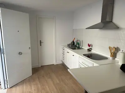 a white kitchen with a sink and a refrigerator at Apartamentos Bajo Guía in Sanlúcar de Barrameda