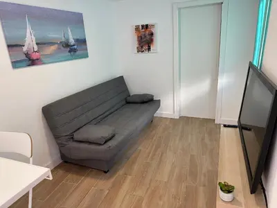 a living room with a couch and a tv at Apartamentos Bajo Guía in Sanlúcar de Barrameda