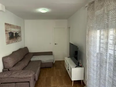 a living room with a couch and a television at Apartamentos Bajo Guía in Sanlúcar de Barrameda