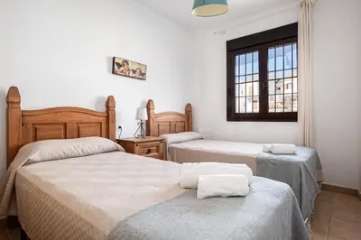 a bedroom with two beds and a window at coto 7 8 in Chiclana de la Frontera