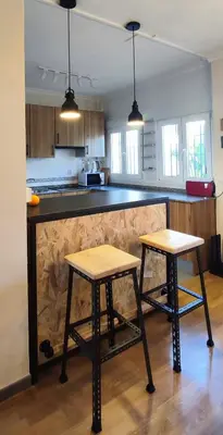 a kitchen with two wooden stools in front of a counter at Dolce Vita Chiclana in Chiclana de la Frontera