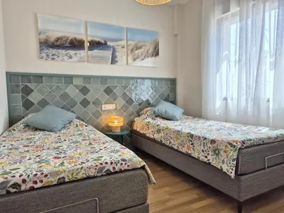 a bedroom with two beds and a table at Dolce Vita Chiclana in Chiclana de la Frontera