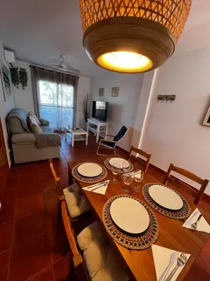 a living room with a wooden table with chairs and a dining room at Apartamento Riviera in Novo Sancti Petri