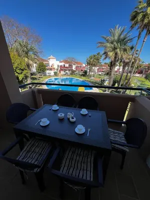 a table and chairs on a balcony with a view of a pool at Apartamento Riviera in Novo Sancti Petri