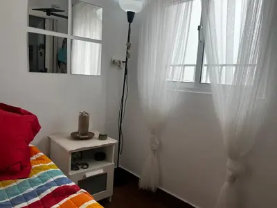 a bedroom with a bed and a window with curtains at El rincón de Malandar in Sanlúcar de Barrameda