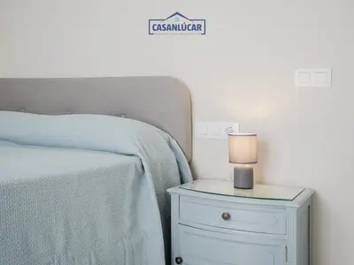 a bedroom with a bed and a nightstand with a candle at Piso Atlantis in Sanlúcar de Barrameda