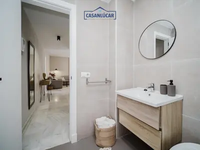 a white bathroom with a sink and a mirror at Piso Atlantis in Sanlúcar de Barrameda