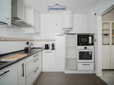 a white kitchen with white cabinets and a microwave at Piso Atlantis in Sanlúcar de Barrameda