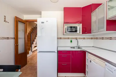 a kitchen with red cabinets and a white refrigerator at Balconera 79 in Chiclana de la Frontera