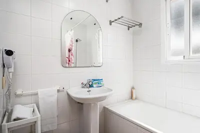 a white bathroom with a sink and a mirror at Balconera 79 in Chiclana de la Frontera