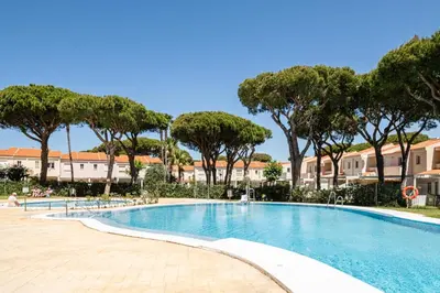 a swimming pool with trees and buildings in the background at Balconera 79 in Chiclana de la Frontera