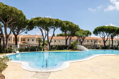 a swimming pool with trees and buildings in the background at Balconera 79 in Chiclana de la Frontera