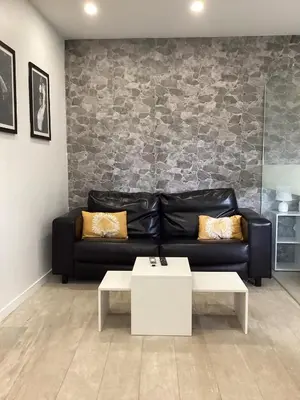 a living room with a black leather couch and a table at Apartamento La Guitarra in Jerez de la Frontera