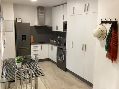 a kitchen with white cabinets and a black refrigerator at Apartamento La Guitarra in Jerez de la Frontera