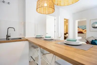 a kitchen with a wooden table with glasses and a sink at Brisa Jerez Suites in Jerez de la Frontera