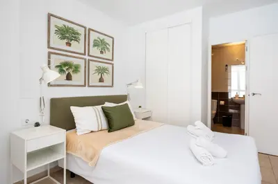 a white bedroom with a bed with white shoes on it at Brisa Jerez Suites in Jerez de la Frontera