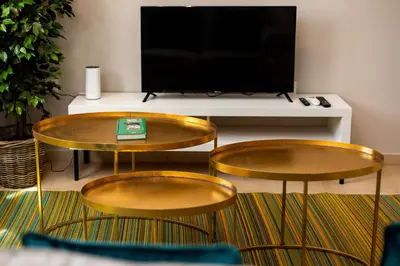 two tables and a tv in a living room at Brisa Jerez Suites in Jerez de la Frontera