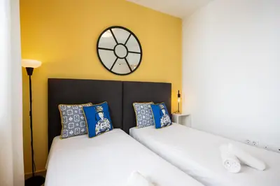 two beds in a bedroom with a clock on the wall at Brisa Jerez Suites in Jerez de la Frontera