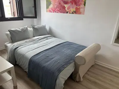 a bed in a bedroom with a painting on the wall at Acogedor apartamento, céntrico, recién restaurado in Jerez de la Frontera