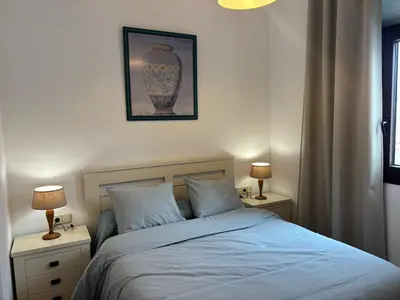 a bedroom with a bed and two night stands with lamps at Acogedor apartamento, céntrico, recién restaurado in Jerez de la Frontera