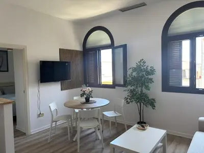 a living room with a table and chairs at Acogedor apartamento, céntrico, recién restaurado in Jerez de la Frontera