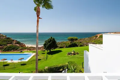 a view of a swimming pool and the ocean at Fuente del Sol in Conil de la Frontera