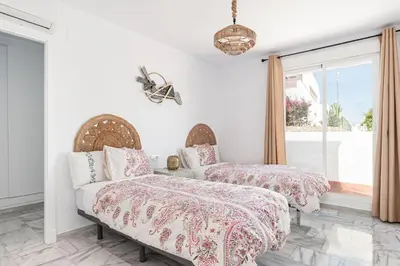 two beds in a room with a window at Fuente del Sol in Conil de la Frontera