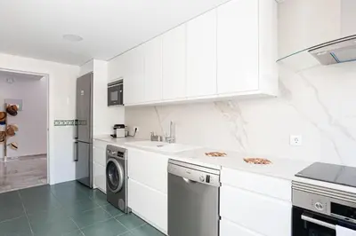 a kitchen with white cabinets and a washer and dryer at Fuente del Sol in Conil de la Frontera
