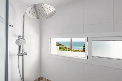 a shower in a white bathroom with a window at Fuente del Sol in Conil de la Frontera