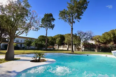 a large blue pool with trees in a park at Hacienda Laguna Seca - Apart. Lavanda in Chiclana de la Frontera