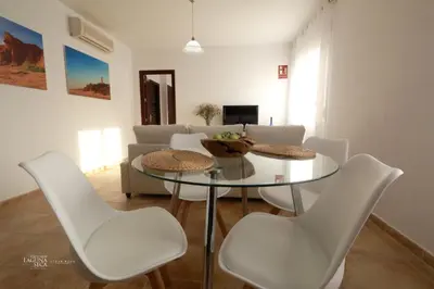 a living room with a glass table and white chairs at Hacienda Laguna Seca - Apart. Lavanda in Chiclana de la Frontera