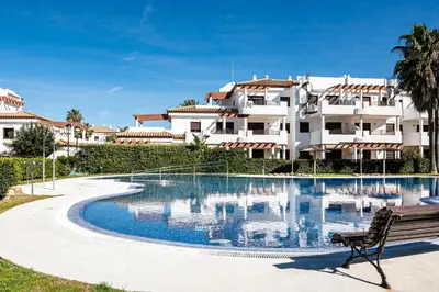 a swimming pool with a bench in front of a building at Coto 10 11 in Chiclana de la Frontera