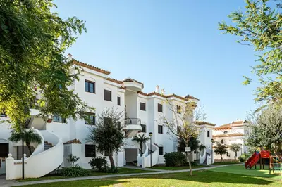 a large white building with a playground in the yard at Coto 10 11 in Chiclana de la Frontera