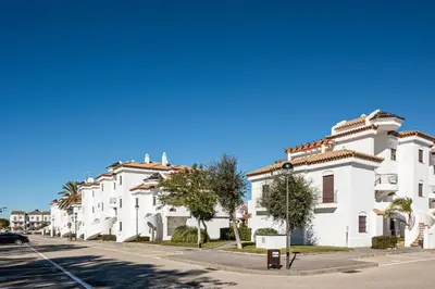 a row of white buildings on a street at coto 4 17 in Chiclana de la Frontera