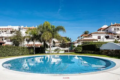 a swimming pool in a villa with palm trees and buildings at coto 8 22 in Chiclana de la Frontera