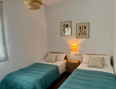 a room with two beds and a light on the wall at Villa Agua Salá in Poblado de Sancti Petri