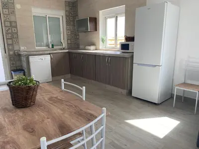 a kitchen with a table and a white refrigerator at Villa Hebane in El Puerto de Santa María