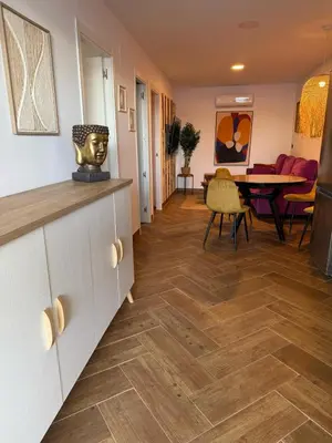 a living room with a wooden floor and a dining room at casitas de las palmeras in Cádiz