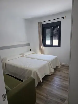 a bedroom with a white bed and a wooden floor at Alojamiento Rural Cortijo Rosario in Conil de la Frontera