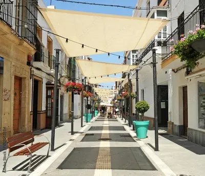 an empty city street with benches and buildings at Estudio patio andaluz in Rota