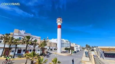 a lighthouse in the middle of a street with palm trees at Estudio patio andaluz in Rota
