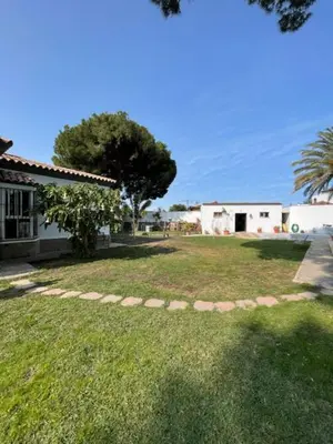 a yard with a house and trees and grass at Villa Clara Chiclana in Chiclana de la Frontera