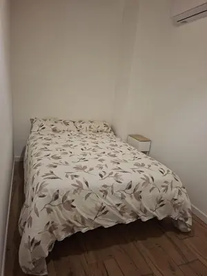 a bed in a white room with a comforter at La Casita de las Piletas in Sanlúcar de Barrameda