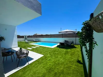 a backyard with a swimming pool and green grass at Villas tesoro del pirata in Conil de la Frontera