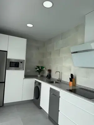 a kitchen with white cabinets and a sink and a dishwasher at Villas tesoro del pirata in Conil de la Frontera