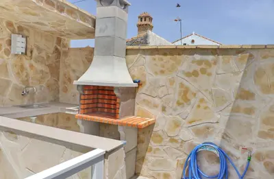 a outdoor kitchen with a stone wall with a stove at Casa el rincón de la Rosa in Conil de la Frontera