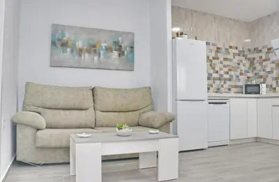 a living room with a couch and a table and a refrigerator at Casa el rincón de la Rosa in Conil de la Frontera