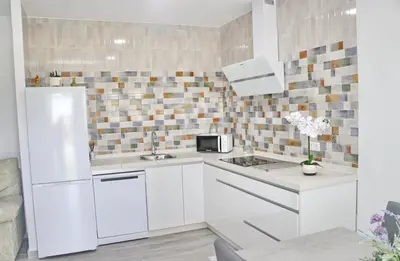 a kitchen with white cabinets and a refrigerator at Casa el rincón de la Rosa in Conil de la Frontera